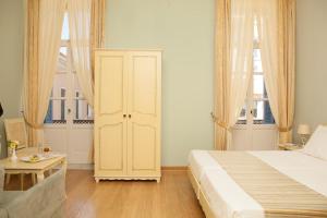 a bedroom with a large bed and two windows at Egli Hotel in Andros