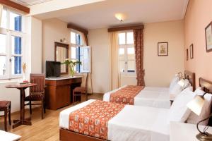 a hotel room with two beds and a desk at Egli Hotel in Andros
