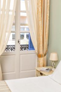 a bedroom with a bed and a window with curtains at Egli Hotel in Andros