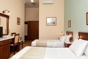 a hotel room with two beds and a desk at Egli Hotel in Andros