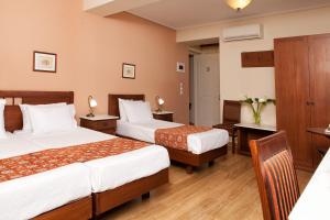 a hotel room with two beds and a table at Egli Hotel in Andros