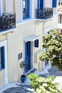 a white building with blue windows and a tree at Egli Hotel in Andros