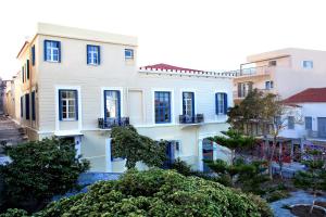 a white house with blue windows and trees at Egli Hotel in Andros