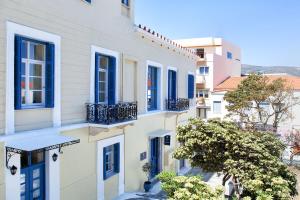 a row of white houses with blue windows at Egli Hotel in Andros