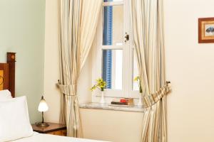 a bedroom with a bed and a window with curtains at Egli Hotel in Andros