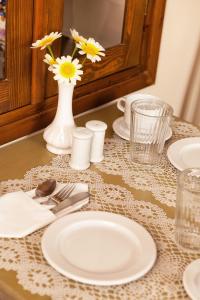 a table with a white plate and a vase of flowers at Egli Hotel in Andros