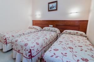 3 camas en una habitación con mantas rojas y blancas en Pensión Isabel by Vivere Stays, en Salamanca