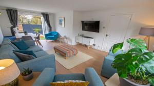 a living room with blue couches and a tv at Oceanside Croyde, Scandi inspired cottage close to Croyde Beach - Sleeps 6 in Croyde