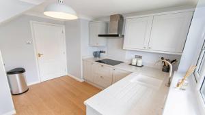 a kitchen with white cabinets and a white counter top at Oceanside Croyde, Scandi inspired cottage close to Croyde Beach - Sleeps 6 in Croyde +4 photos