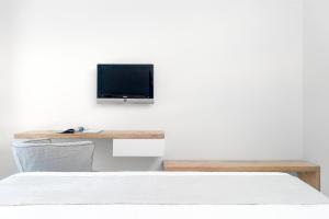 a bedroom with a bed and a tv on a wall at Armonia Bay Hotel in Kokkari