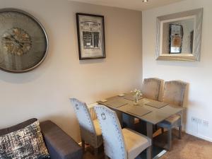 a dining room with a table and chairs and a clock at Bowness On Windermere, Lovely Apartment for 4 With Parking in Bowness-on-Windermere
