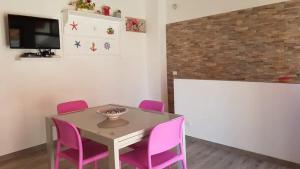 ein Esszimmer mit einem Tisch und rosa Stühlen in der Unterkunft La Perla Bianca in Castellammare del Golfo