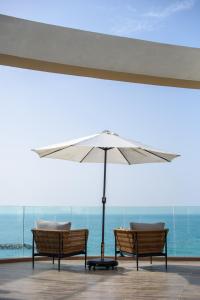 two chairs and an umbrella in front of the ocean at Dream Penthouse in Haifa