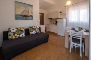 a living room with a couch and a kitchen with a table at Apartmani "MARKO" Dugovača in Drage