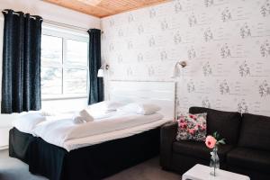 a bedroom with a bed and a couch and a window at Djupvasshytta Bed & Breakfast in Geiranger