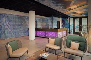 a lobby with chairs and a table and a bar at Inntel Hotels Den Haag Marina Beach in Scheveningen
