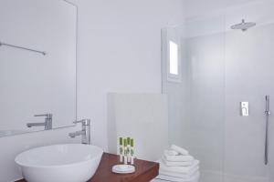 a bathroom with a white tub and a sink at Notos Therme and Spa by Mr and Mrs White in Vlychada