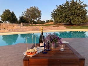 - une table avec une bouteille de vin et de la nourriture à côté de la piscine dans l'établissement Le Cave di Fontane Bianche, à Cassibile