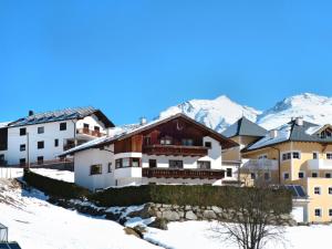 a building in the snow with mountains in the background at Apartment Kassler - KPL602 by Interhome in Kappl