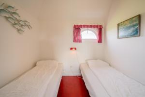 Dos camas en una habitación pequeña con ventana. en Schapenboet de Boet Waalenburg, en De Koog