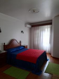 1 dormitorio con 1 cama con sábanas coloridas y ventana en Residencial das Trinas 2, en Guimarães