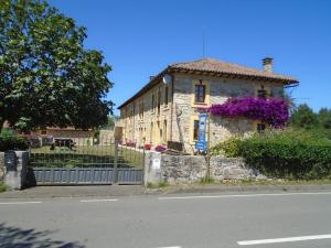 an old stone house with purple flowers on it at Turismo Rural El Gobernador in Villaviciosa