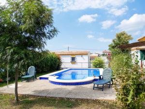 een zwembad met 2 stoelen en een boom bij Holiday Home Hanna - CHZ300 by Interhome in Chiclana de la Frontera