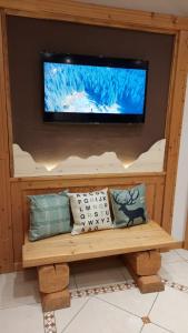 TV en una pared sobre un banco con almohadas en Hotel Angelo, en Comano Terme