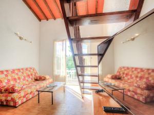 a living room with two couches and a spiral staircase at Holiday Home Les Villas de l'Aygual by Interhome in Saint-Cyprien-Plage