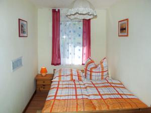 een slaapkamer met een bed en een raam met rode gordijnen bij Holiday Home Am Walde-1 by Interhome in Dobbertin