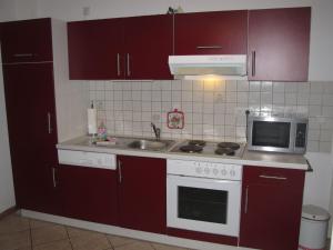 een keuken met rode kasten, een wastafel en een magnetron bij Apartment Wildrose by Interhome in Zempin