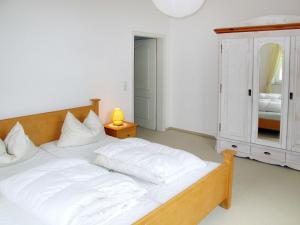 a bedroom with a bed with white sheets and a cabinet at Apartment Wildrose by Interhome in Zempin