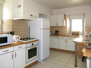 a kitchen with white cabinets and a white refrigerator at Holiday Home Le Petit Maître by Interhome in Le Tronchet