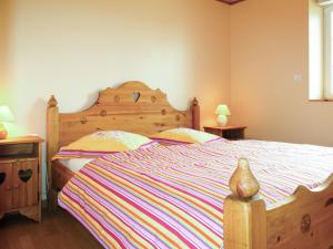 ein Schlafzimmer mit einem Holzbett mit einer gestreiften Decke in der Unterkunft Holiday Home Milin-Avel - TGM102 by Interhome in Telgruc-sur-Mer