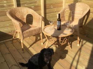 a black dog sitting next to a table with a bottle of wine at Angels Corner, Ventnor Bay in Ventnor