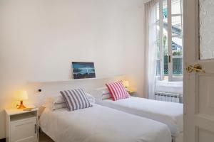 dwa łóżka w pokoju z oknem w obiekcie A pochi passi da Piazza de Ferrari by Wonderful Italy w Genui
