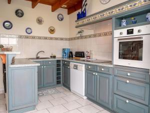 a blue kitchen with white appliances and blue plates on the wall at Holiday Home Pors Bae - PMN102 by Interhome in Primelin
