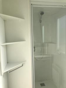 La salle de bains est pourvue d'une douche et d'une porte en verre. dans l'établissement CAMP'HOTEL LE THAO LA ROCHELLE-ILE DE RE, à LʼHoumeau