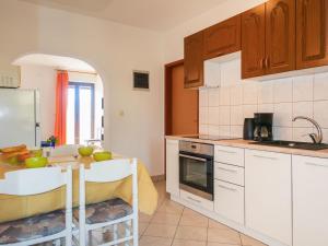 a kitchen with white cabinets and a table with green bowls on it at Apartment Rosić - KRK218 by Interhome in Kornić