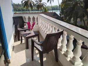 un balcón con 2 sillas y una mesa con flores en Valeria's Holiday Home, en Cavelossim
