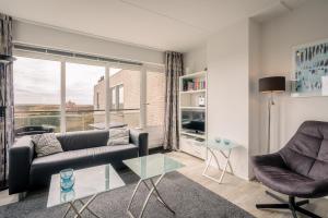 Una sala de estar con un sofá y sillas y una ventana. en Appartementencomplex Juliana 132, en De Koog