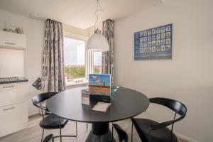 Un comedor con mesa y sillas y una ventana. en Appartementencomplex Juliana 132, en De Koog 3 fotos más