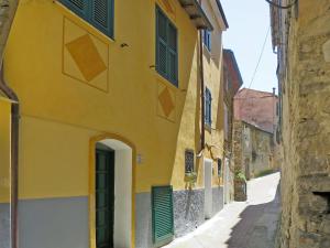 a yellow building with green shutters on a street at Apartment Le Volte - PTB190 by Interhome in Pietrabruna
