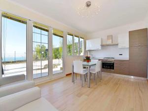 uma cozinha com mesa, cadeiras e janelas em Apartment Primavera - PGI132 by Interhome em Poggi