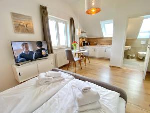 a bedroom with a bed with a tv and a kitchen at mönchgut living & spa in Gager
