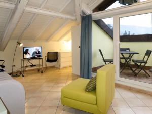 uma sala de estar com uma cadeira amarela e uma televisão em Apartment del Sole-3 by Interhome em Luino