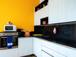 una cucina con armadi bianchi e piano di lavoro nero di Apartment del Sole-5 by Interhome a Luino