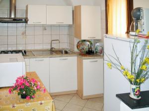 uma cozinha com armários brancos e uma mesa com flores em Apartment Elisa - DOL127 by Interhome em Costa Carnara