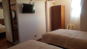 a hotel room with two beds and a flat screen tv at Asian House in Uyuni