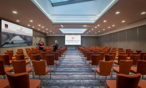 una sala conferenze con sedie e due persone sullo schermo di Clayton Hotel Cardiff Lane a Dublino Altre 37 foto